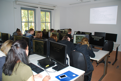 Gruppe von Schülerinnen und Schülern vor Computern beim Anwenden der Software Google Earth Pro